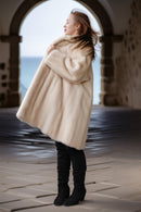 Pearl mink swing coat with hood, cream fur, full flared hem over tall boots