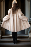 Mink swing coat back view, hooded cream fur, wide flared hem over boots