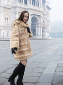 Blond pastel mink fur coat stroller jacket in a foggy cityscape, showcasing luxury fur fashion for cold-weather elegance.