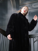 Person wearing a black coat in an indoor setting with decorative elements.