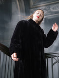 Person wearing a black coat in an indoor setting with decorative elements.