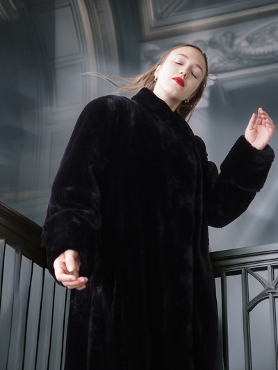 Person wearing a black coat in an indoor setting with decorative elements.
