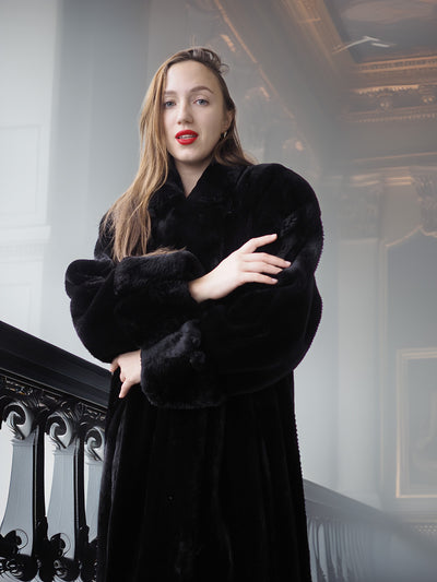 Woman wearing a black fur coat in an elegant interior setting