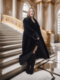 Woman in a black coat standing on a grand staircase with classical architecture.