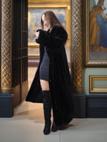 Woman in a long black coat standing in an art gallery