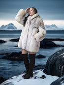 Woman in a fur coat standing on a snowy landscape with mountains in the background
