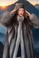 Person wearing a fur coat and hat with a mountainous background