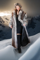 Woman in a fur coat and hat standing on a snowy mountain