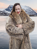Model embracing plush Finnish Raccoon Fur Coat with thick collar, highlighting natural fur texture and warmth near icy lake.