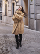 Golden Reverie M - Cozy blond mink coat with high collar, styled for winter elegance on a cobblestone street.