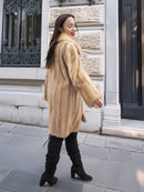Golden Reverie M - Rear view of flowing mink coat in beige tones, styled with black boots for a chic urban look.
