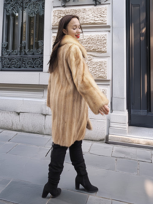 Golden Reverie M - Rear view of flowing mink coat in beige tones, styled with black boots for a chic urban look.