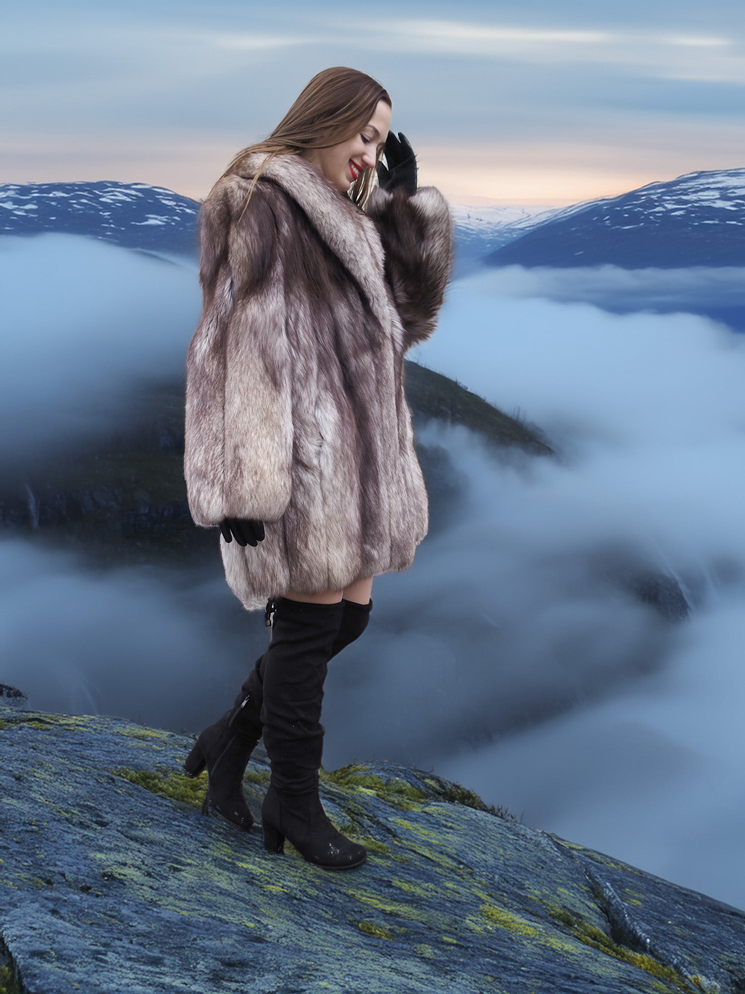 Plush blue fox coat with large shawl collar and full silhouette, modeled on a cliff above the clouds. High-end fur outerwear for winter elegance.