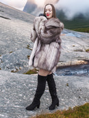 Brand new silver fox fur coat with soft, fluffy pelts and wide collar, modeled on rocky terrain. Real fur outerwear for cold weather fashion.