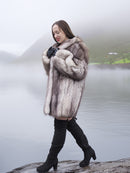 Real fox fur coat in silver-blue tones with large collar, worn by model walking near a misty lake. Stylish and warm outerwear for winter fashion.