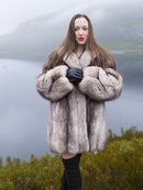 Plush soft blue fox coat with thick shawl collar and full sleeves, modeled in a scenic mountain setting. High-end fur jacket for luxury outerwear lovers.