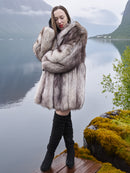 Brand new silver-blue fox fur coat with elegant drape and cozy fit, worn near a mossy lakeside. Real fur fashion outerwear in medium/large size.