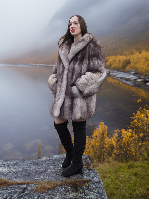 Luxury blue fox fur coat with natural silver tones, modeled in an autumn mountain landscape. Premium fur outerwear for stylish cold-weather wear.