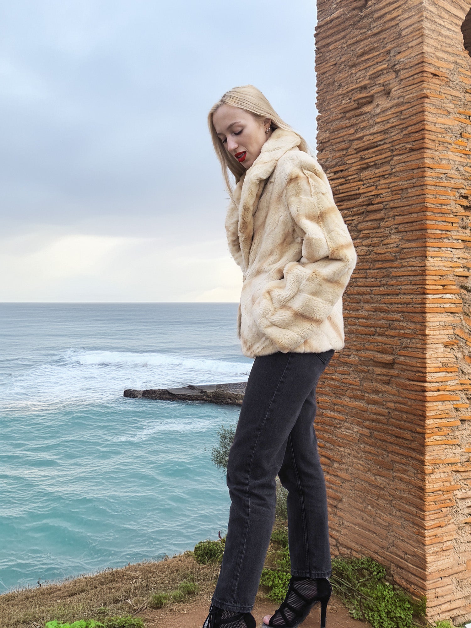 Reversible Versatile Sheared Mink Fur Jacket Coat S in soft fur finish, modeled near sea cliffs with brick tower backdrop.