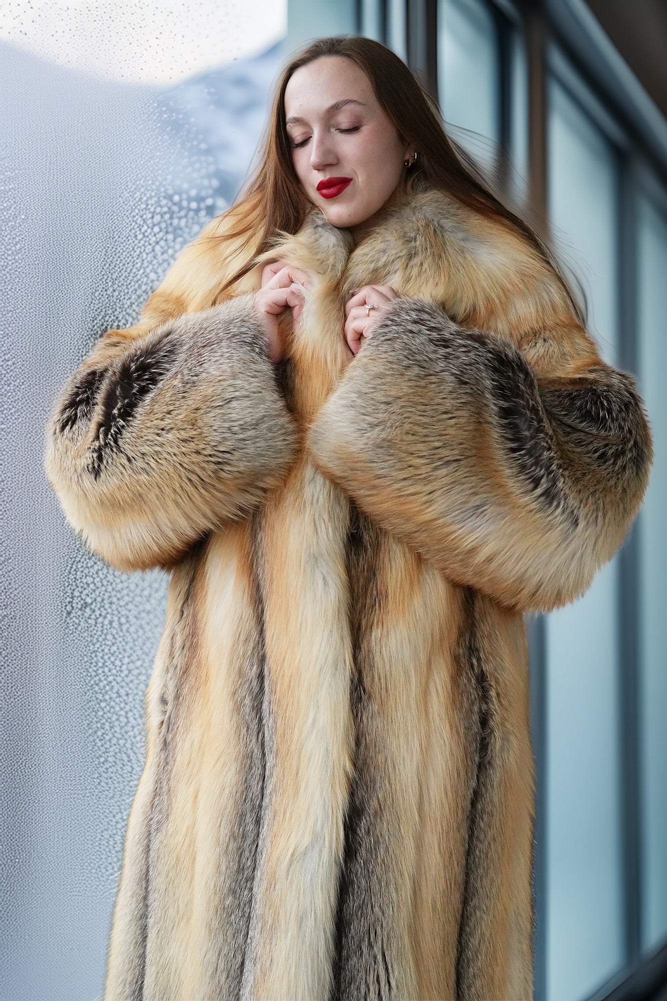 Woman wearing a fur coat standing against a blurred indoor background