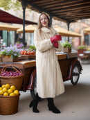 Woman in a fur coat and red gloves standing next to a vintage car with fruit baskets.