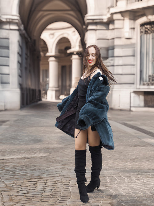 Model twirls in The Still Hour deep teal fur coat, revealing its flowing cut and plush texture for statement winter outerwear.