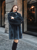 Model embraces warmth in The Still Hour deep teal sheared muskrat fur coat, ideal for luxury cold-weather outerwear collections.