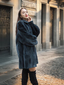 The Still Hour sheared muskrat fur coat in deep teal styled with red lipstick and black boots, ideal for elegant winter fashion.