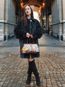 The Still Hour deep teal sheared muskrat fur coat styled with a colorful handbag and black boots, perfect for luxury fur fashion.