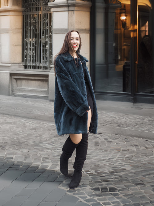 Smiling model showcases The Still Hour deep teal sheared muskrat fur coat, a luxurious and rare vintage outerwear piece for cold seasons.