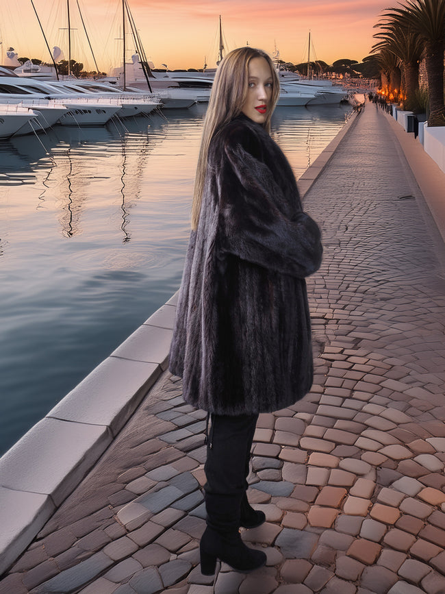 Woman in a fur coat standing by a waterfront at sunset
