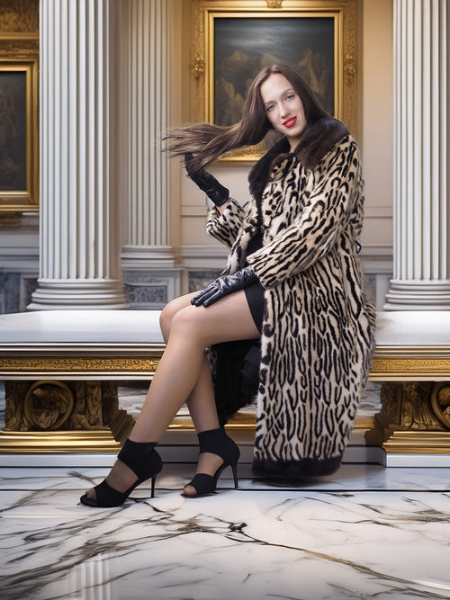 Woman in a leopard print coat sitting on a marble bench in an elegant interior setting.