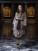 Woman wearing a leopard print coat in an elegant interior setting with classical architecture.