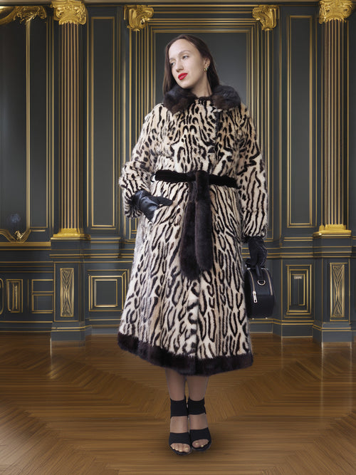 Woman wearing a leopard print coat with fur trim in an ornate room.
