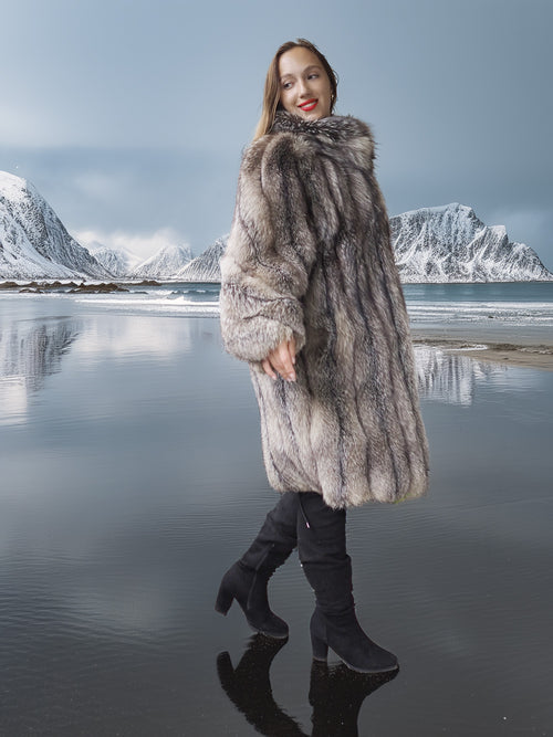 Woman in a fur coat standing on a reflective water surface with snowy mountains in the background
