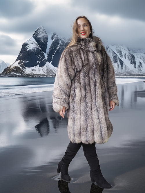Person wearing a fur coat standing in front of a mountainous landscape.