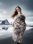Woman wearing a fur coat with a mountainous landscape in the background