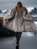 Person wearing a fur coat with a mountainous landscape in the background