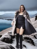 Woman in a fur coat standing on a snowy landscape with mountains in the background