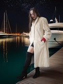 Woman in a fur coat standing on a dock with yachts in the background