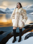 Woman in a fur coat standing in a snowy landscape with mountains and water.