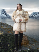 Woman in a fur coat standing in a mountainous landscape