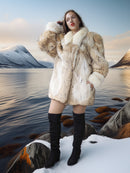 Woman in a fur coat standing on a snowy landscape with mountains and water in the background