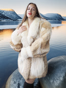Woman in a fur coat standing on a rock with a scenic background