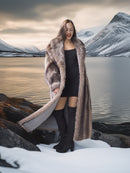 Woman in a fur coat standing in a snowy landscape with mountains in the background