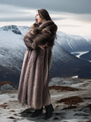 Woman in a fur coat standing in a snowy mountain landscape
