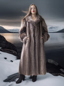 Woman in a fur coat standing in a snowy landscape with mountains in the background