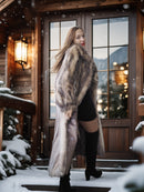Woman in a fur coat standing in front of a wooden door with snow-covered landscape.