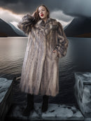 Woman wearing a fur coat in a surreal landscape with mountains and a dark sky.
