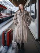 Woman in a fur coat with a red suitcase at a train station